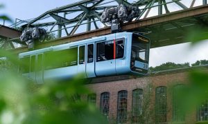 Die Wuppertaler Schwebebahn fotografiert aus einem Winkel mit Sträuchern