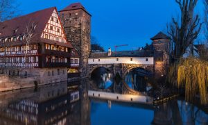 Eine Hausfassade mit Wasser davor in Nürnberg nach Einbruch der Dämmerung